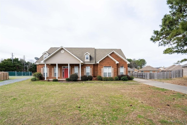 view of front facade featuring fence, a front lawn, and brick siding