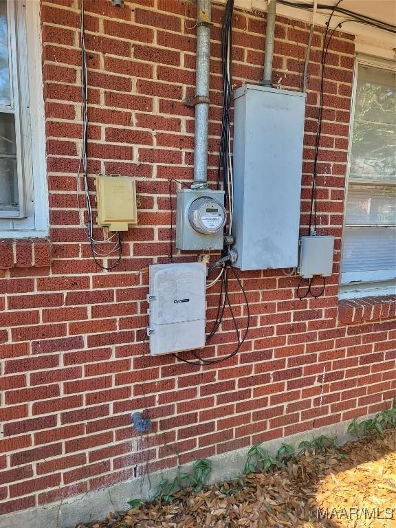 exterior details with electric meter, brick siding, and a wood stove