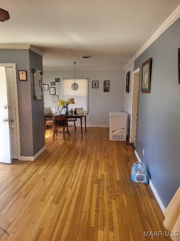 dining room featuring baseboards, light wood-type flooring, and crown molding