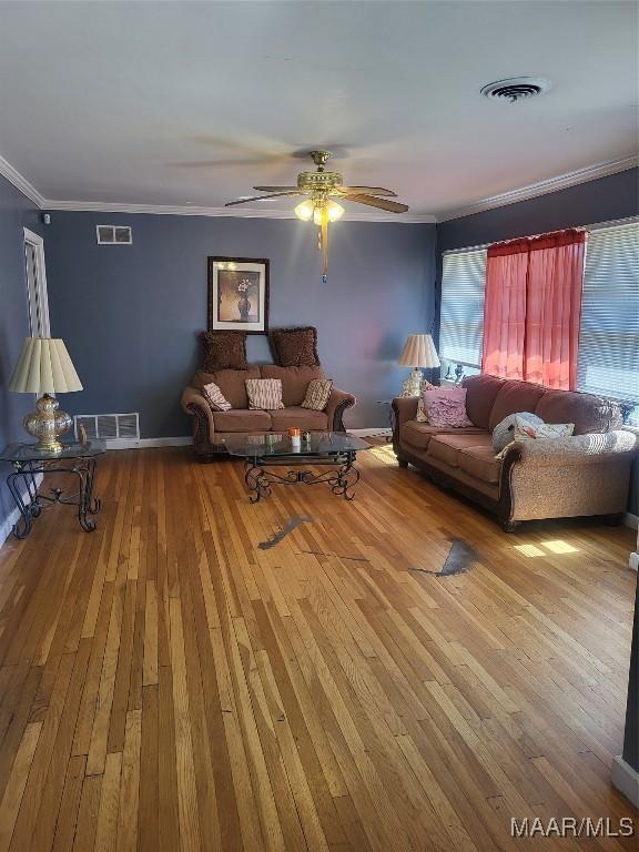 unfurnished living room with wood-type flooring, visible vents, and crown molding