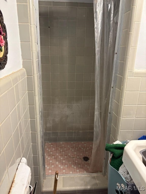 bathroom with a shower stall and tile walls