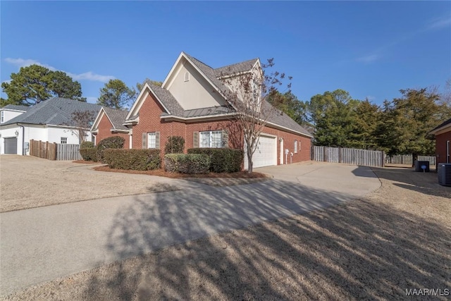 view of front of property with a standing seam roof, fence, concrete driveway, and brick siding