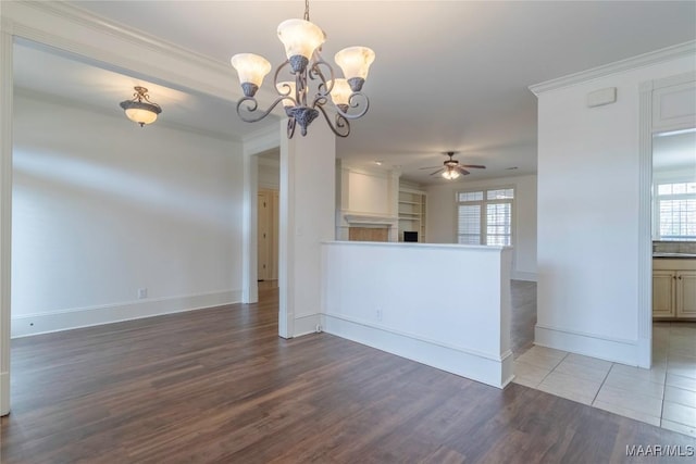 unfurnished room featuring ceiling fan with notable chandelier, plenty of natural light, wood finished floors, and crown molding