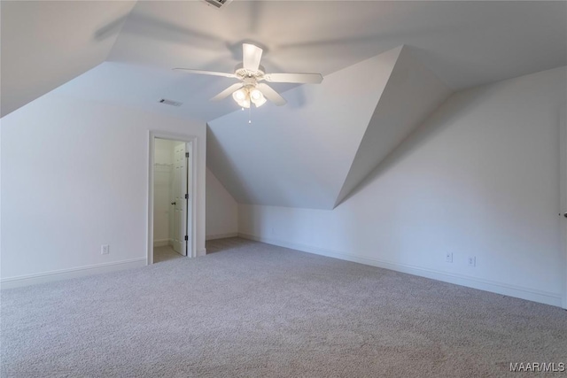 additional living space with visible vents, a ceiling fan, light carpet, vaulted ceiling, and baseboards