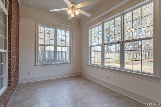 tiled empty room featuring a ceiling fan, a wealth of natural light, and baseboards