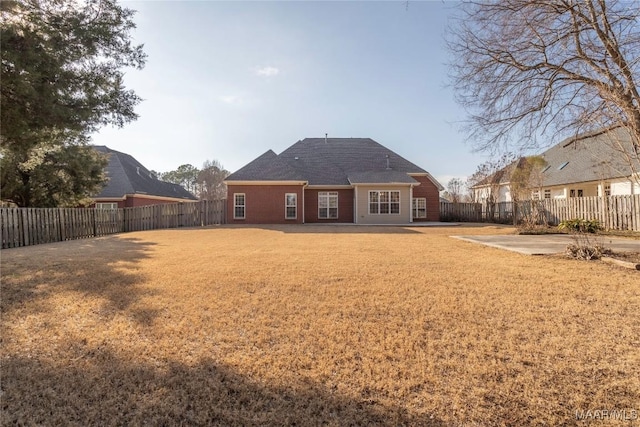 rear view of property featuring a patio area, a fenced backyard, and a lawn