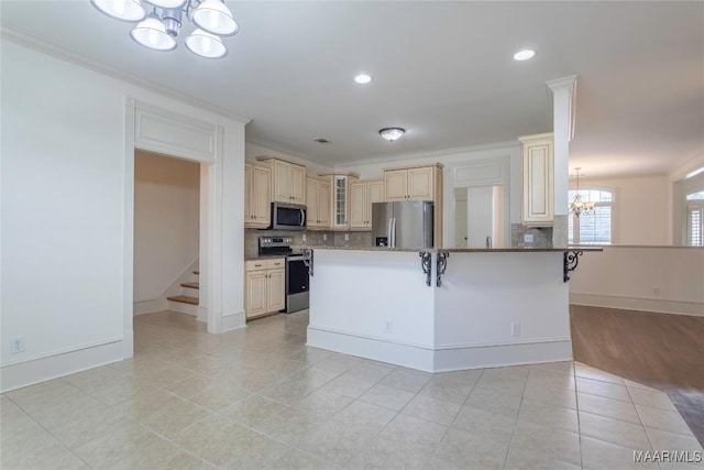 kitchen with appliances with stainless steel finishes, glass insert cabinets, a breakfast bar area, cream cabinets, and a notable chandelier