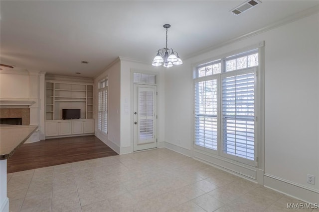 unfurnished living room with a chandelier, visible vents, baseboards, a tiled fireplace, and crown molding