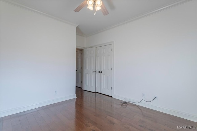 unfurnished bedroom featuring a closet, baseboards, crown molding, and wood finished floors