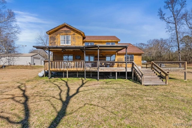 rear view of house with a deck, a yard, stairway, and an outbuilding