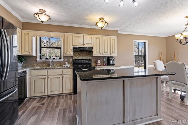 kitchen featuring electric stove, wood finished floors, freestanding refrigerator, cream cabinets, and under cabinet range hood