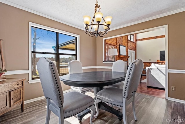 dining space with a textured ceiling, wood finished floors, baseboards, ornamental molding, and an inviting chandelier