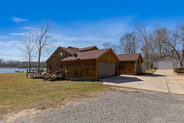 view of front of property featuring a water view, a detached garage, a front lawn, and roof with shingles