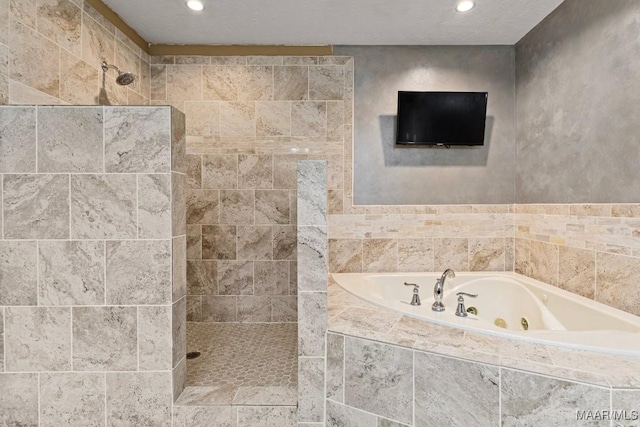 bathroom with a tub with jets, a tile shower, a textured ceiling, and recessed lighting