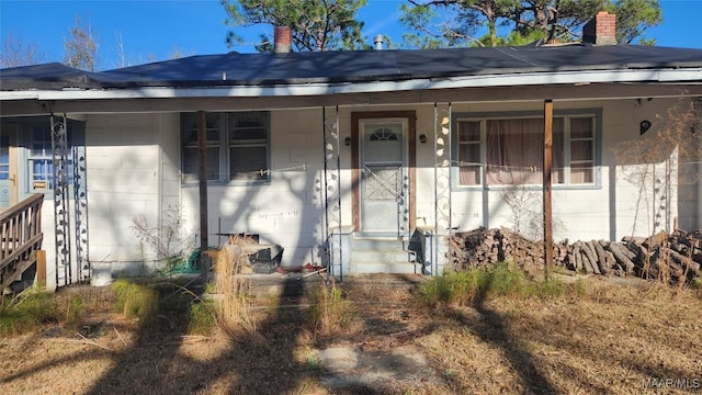 doorway to property with a chimney and a porch