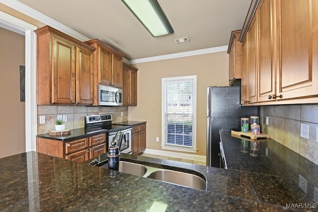 kitchen with a sink, visible vents, ornamental molding, appliances with stainless steel finishes, and brown cabinets