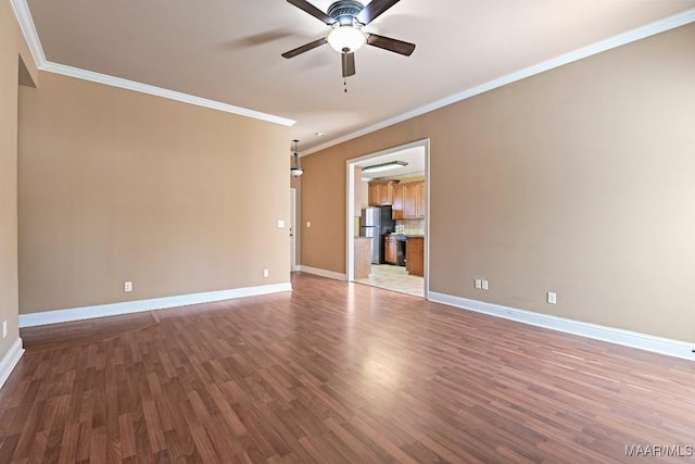 empty room featuring ceiling fan, crown molding, baseboards, and wood finished floors