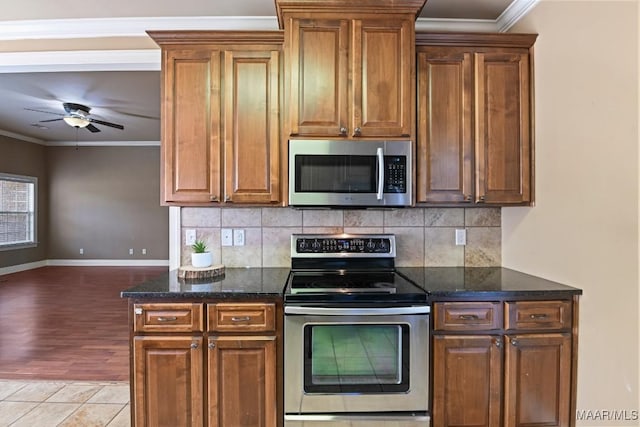 kitchen featuring brown cabinetry, decorative backsplash, ceiling fan, appliances with stainless steel finishes, and ornamental molding