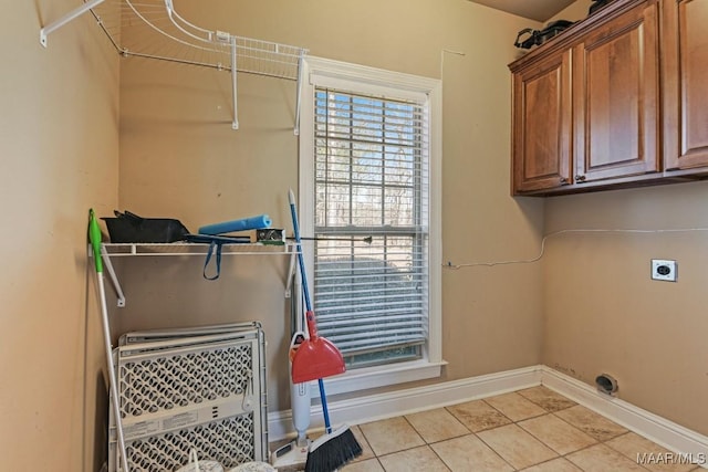 laundry area with cabinet space, baseboards, hookup for an electric dryer, and light tile patterned flooring