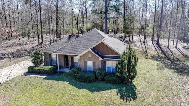 view of front of property with roof with shingles, a front yard, and brick siding