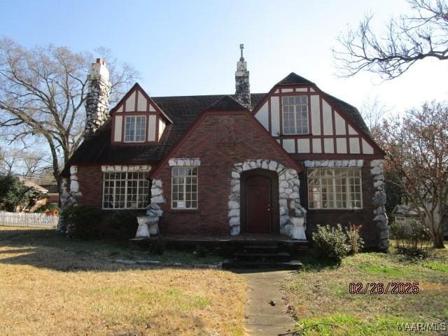 tudor house featuring a chimney and a front yard