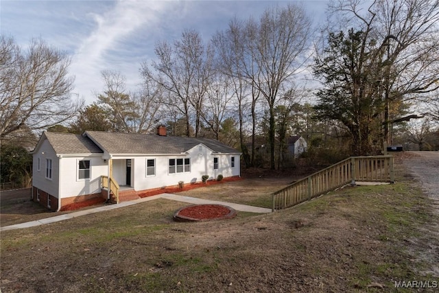 view of front of property featuring a front yard, brick siding, and a chimney