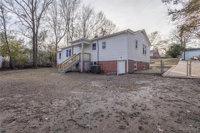 rear view of property featuring brick siding, fence, a gate, and central air condition unit