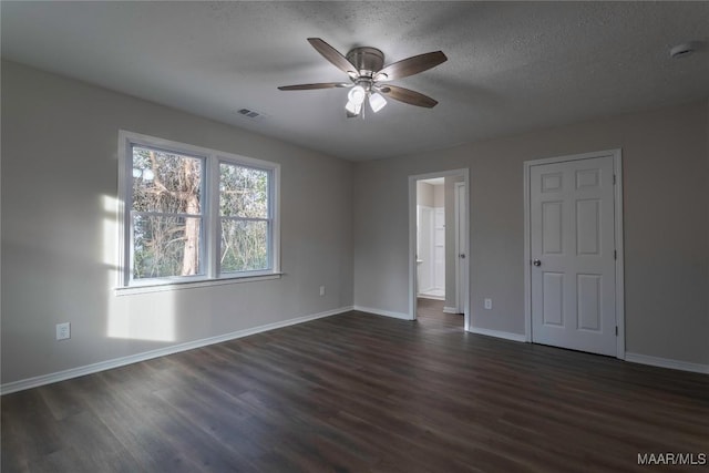 unfurnished room featuring a textured ceiling, dark wood-style flooring, visible vents, and baseboards