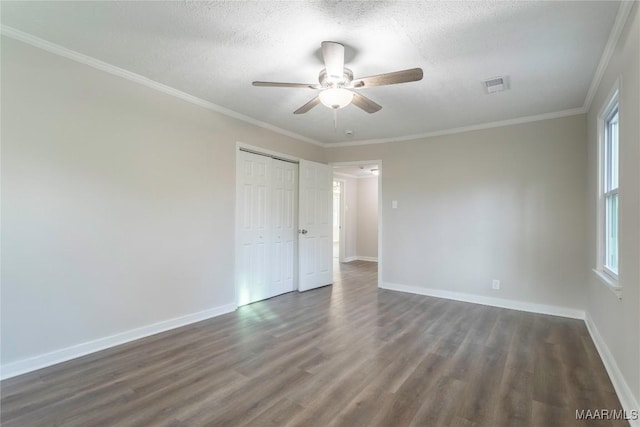 unfurnished bedroom featuring baseboards, visible vents, dark wood-type flooring, a textured ceiling, and crown molding