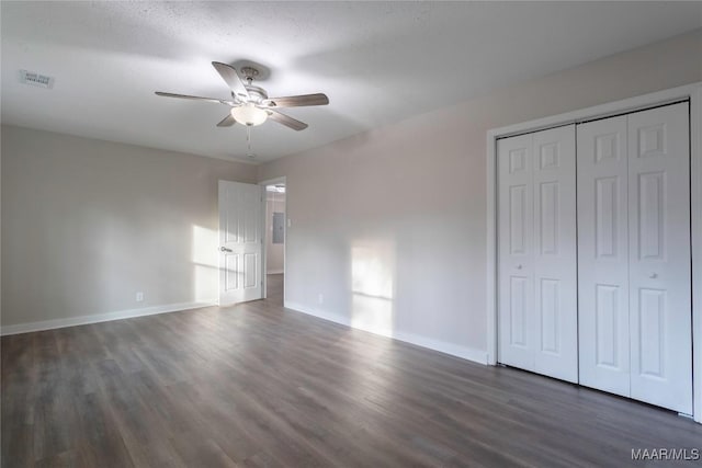 unfurnished bedroom featuring ceiling fan, wood finished floors, visible vents, baseboards, and a closet