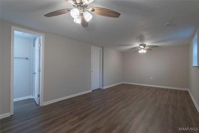 empty room with dark wood-style flooring, a ceiling fan, and baseboards