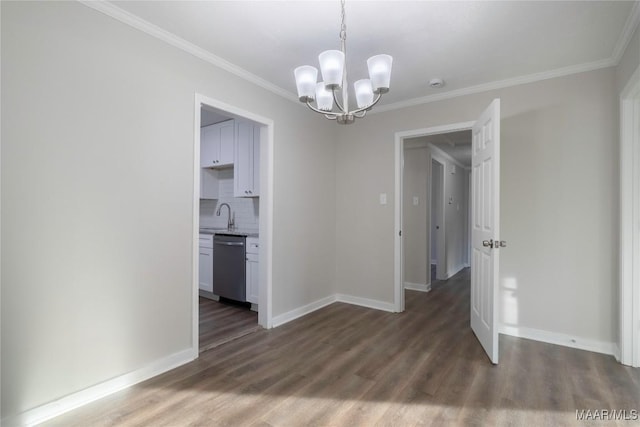 unfurnished dining area with a notable chandelier, ornamental molding, a sink, wood finished floors, and baseboards