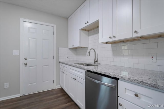 kitchen featuring dark wood-style floors, light stone counters, stainless steel dishwasher, white cabinetry, and a sink