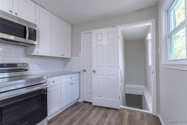 kitchen with tasteful backsplash, appliances with stainless steel finishes, dark wood-type flooring, and white cabinets