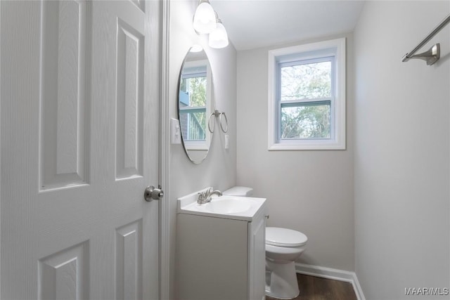 bathroom with baseboards, vanity, toilet, and wood finished floors