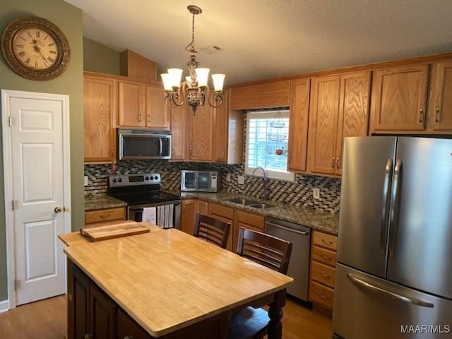 kitchen featuring tasteful backsplash, a sink, stainless steel appliances, wooden counters, and a notable chandelier