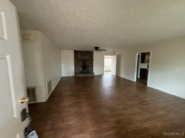 unfurnished living room featuring a fireplace, visible vents, ceiling fan, a textured ceiling, and baseboards