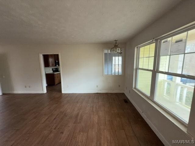 interior space featuring baseboards, dark wood-style flooring, a textured ceiling, and an inviting chandelier