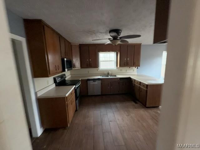 kitchen featuring dishwasher, stainless steel microwave, wood finished floors, black range with electric cooktop, and a sink