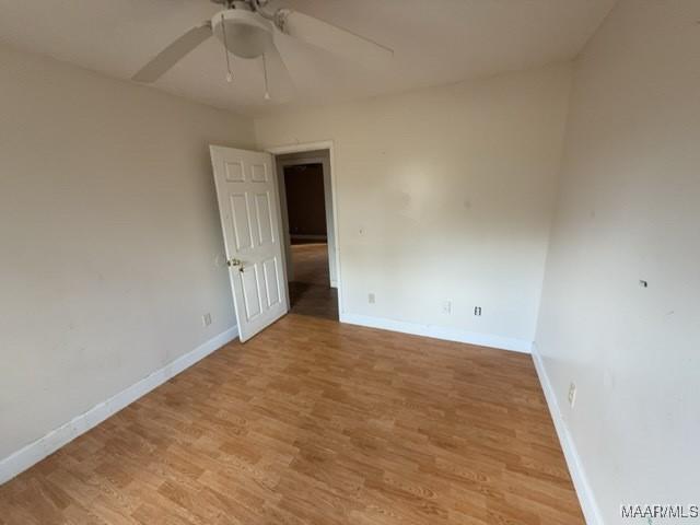 empty room with baseboards, ceiling fan, and light wood-style floors