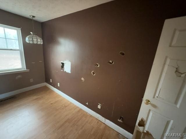 interior space featuring a textured ceiling, light wood finished floors, and baseboards