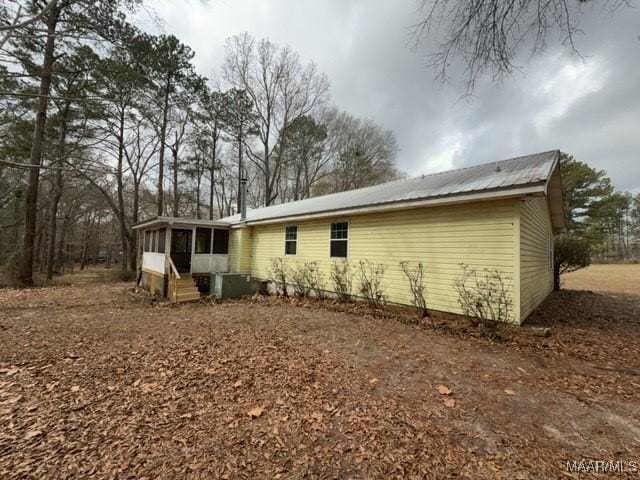 view of side of property with a sunroom, central AC, and metal roof