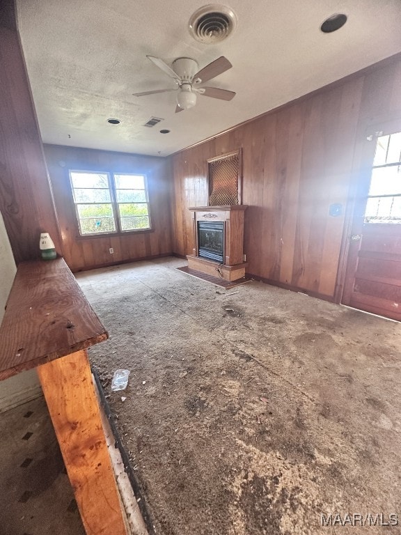 unfurnished living room with ceiling fan, visible vents, a textured ceiling, and a glass covered fireplace