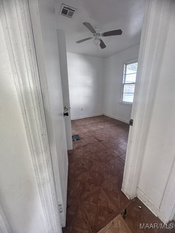 empty room with baseboards, visible vents, and ceiling fan