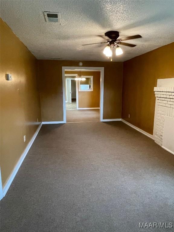 carpeted spare room featuring ceiling fan, a textured ceiling, visible vents, and baseboards