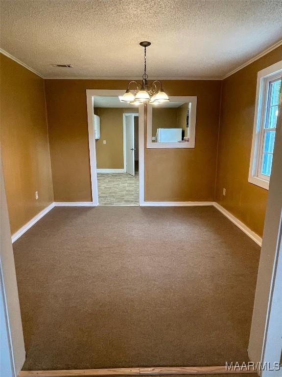 carpeted empty room with a chandelier, crown molding, a textured ceiling, and baseboards