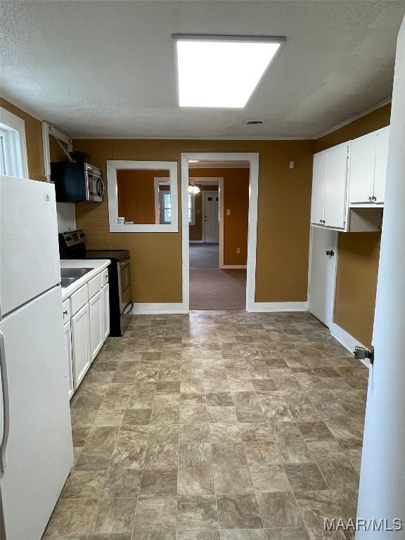 kitchen with appliances with stainless steel finishes, white cabinets, and baseboards