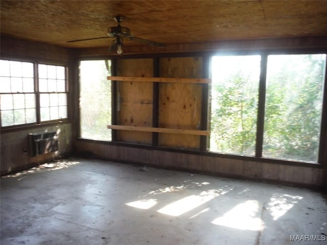 unfurnished room with concrete flooring, wooden walls, a wall mounted AC, and a healthy amount of sunlight