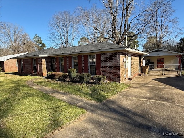 view of front of house with driveway, brick siding, and a front yard