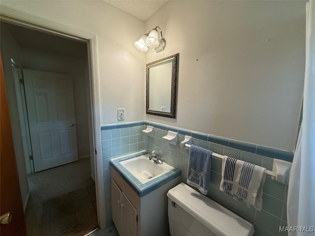 20 Glendale Dr, Selma, AL 36701 - bathroom featuring vanity, a textured ceiling, toilet, a wainscoted wall, and tile walls